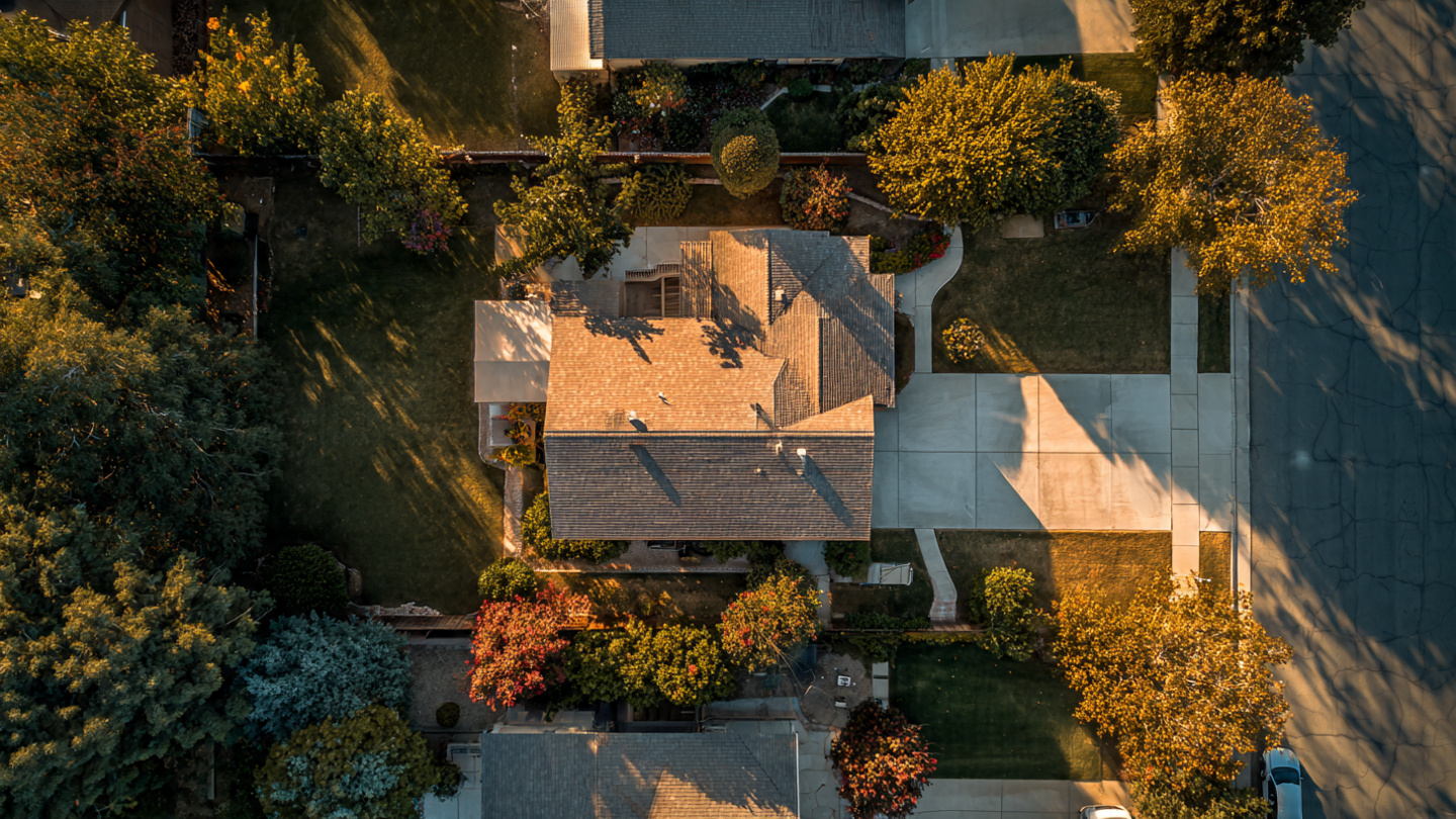 Satellite view of a residential neighborhood with colored overlays indicating AI-scored property conditions on different rooftops