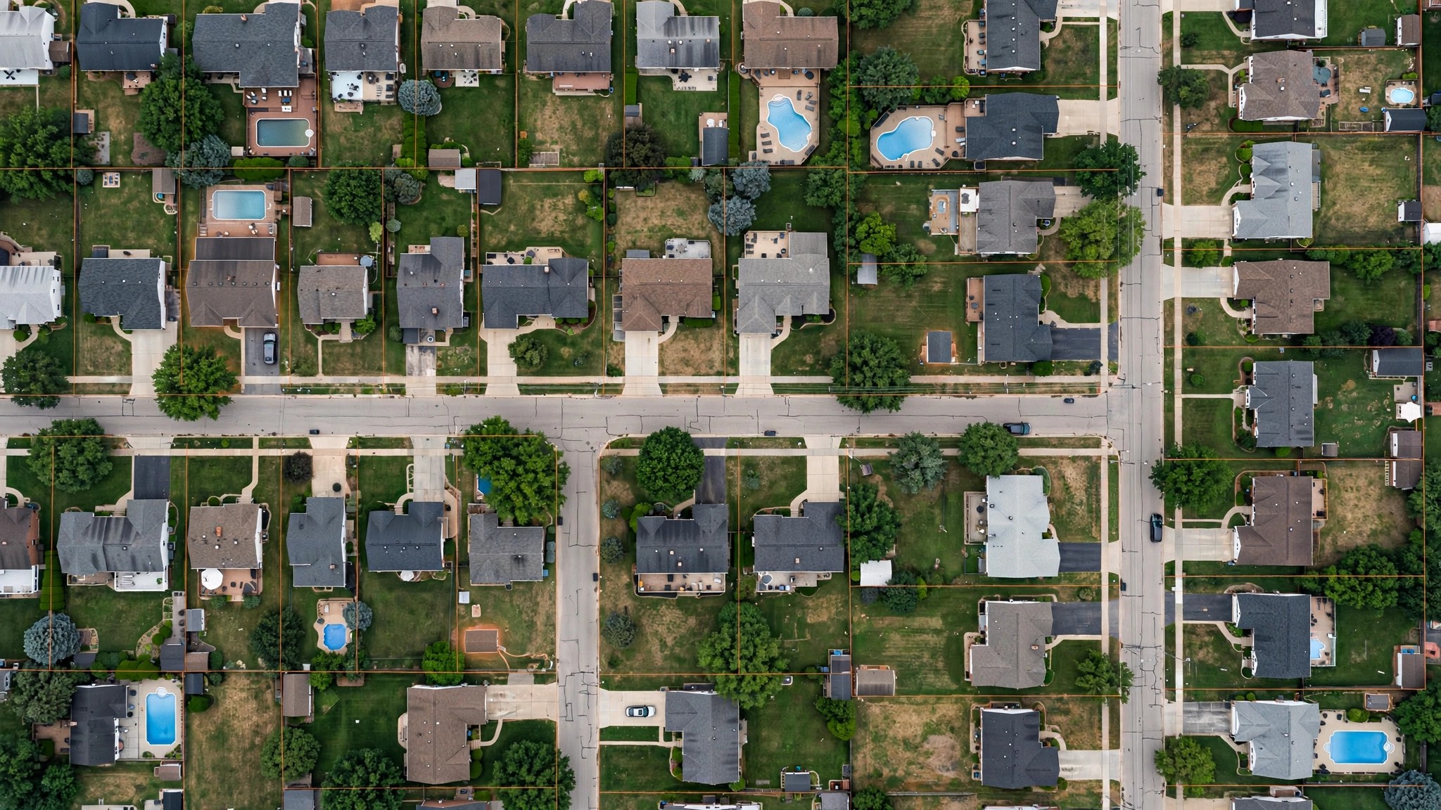Aerial satellite view of suburban neighborhood backyards showing pools, additions, and outbuildings with property boundary lines overlaid, warm afternoon light