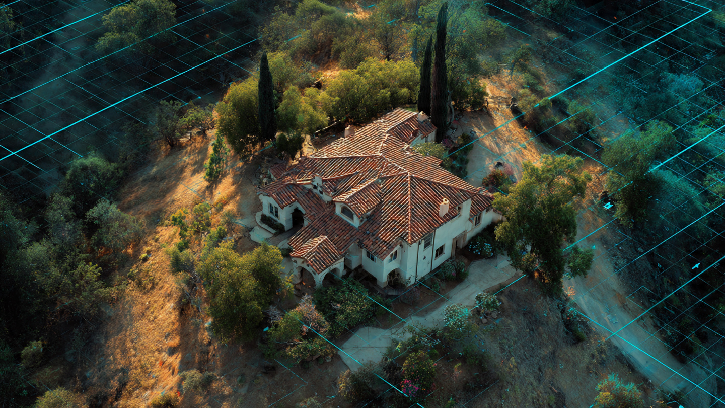 Aerial satellite view of a California hillside neighborhood showing varied vegetation density and rooftop materials, with some properties cleared and defensible while adjacent lots are overgrown with dry brush
