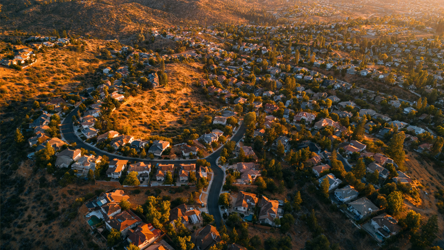 Aerial view of California hillside homes with AI risk overlay heat map highlighting construction materials and vegetation zones
