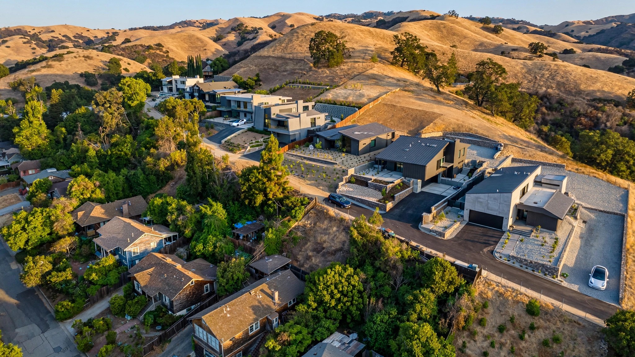 Aerial view of a California hillside neighborhood where some homes have fire-resistant metal roofing and cleared defensible space while neighboring houses have wood shake roofs and dense vegetation, with a semi-transparent heat map overlay in red and green tones