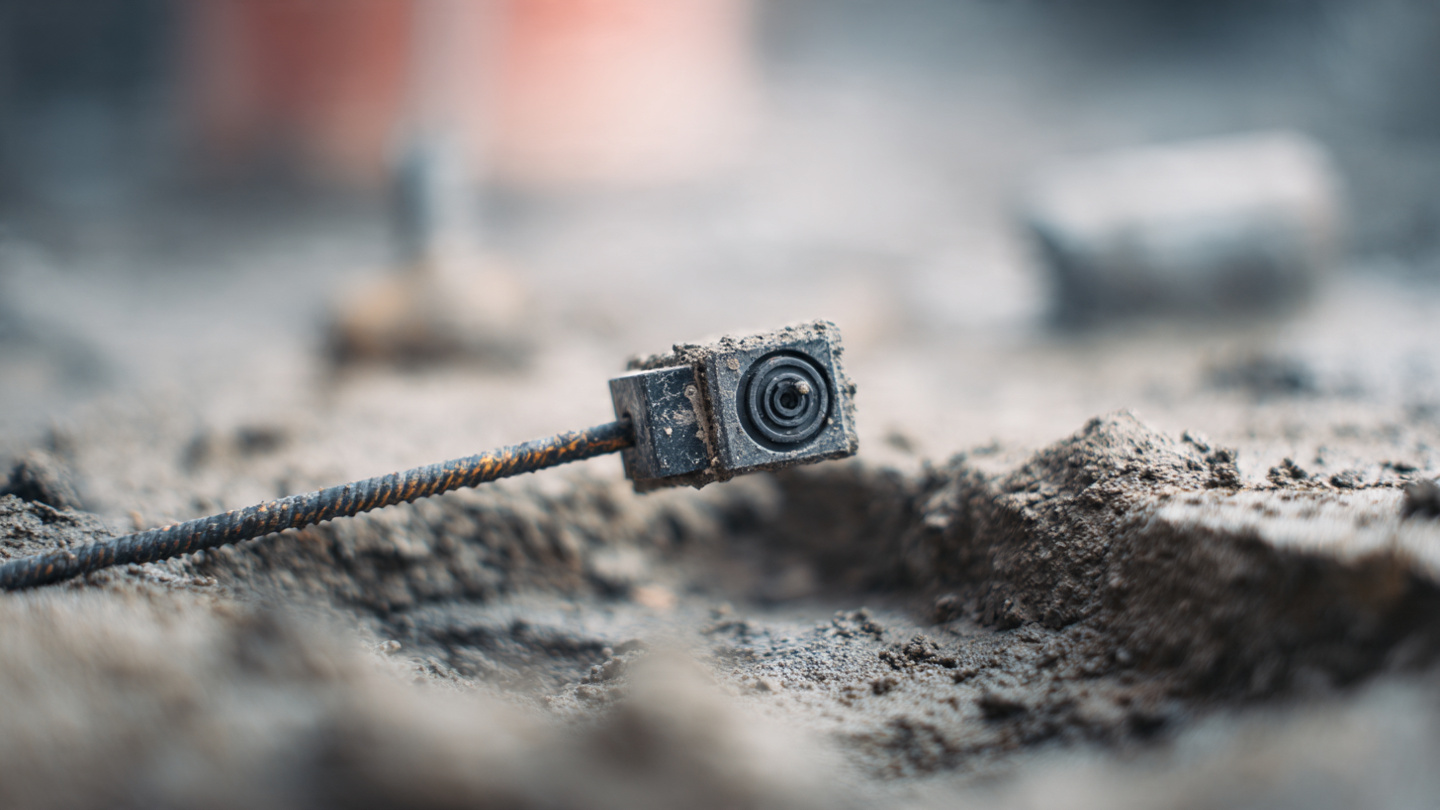 A wireless concrete maturity sensor with a short antenna embedded in steel rebar inside a freshly poured residential foundation